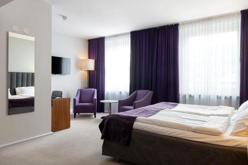 a hotel room with a bed and two chairs at Elite Stadshotellet Eskilstuna in Eskilstuna