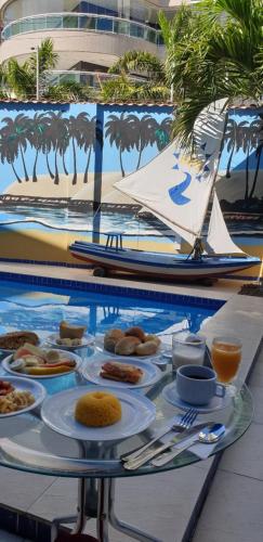 een tafel met borden eten op een tafel met een boot bij Hotel Encontro do Sol in Fortaleza