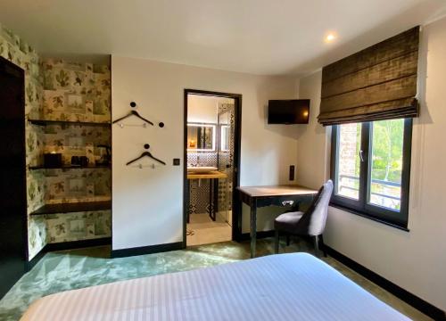 a bedroom with a bed and a desk and a mirror at Le Moulin Fouret in Saint-Aubin-le-Vertueux