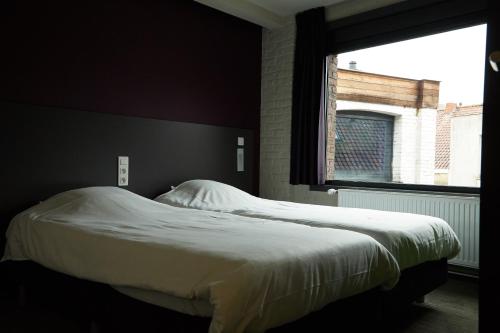 a bed in a bedroom with a large window at Focus Budget in Kortrijk