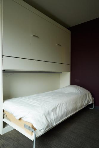 a bedroom with a bed with white sheets and cabinets at Focus Budget in Kortrijk
