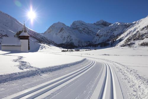 a road covered in snow with a church and mountains at Boutique-Hotel Garni Bellevue Davos Wiesen in Wiesen