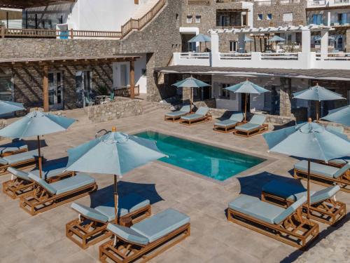 an outdoor swimming pool with lounge chairs and umbrellas at Argo Hotel in Platis Yialos Mykonos