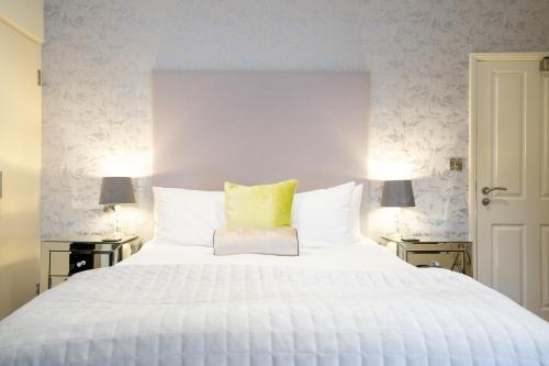 a bedroom with a large white bed with a yellow pillow at The Bear & Swan in Bristol