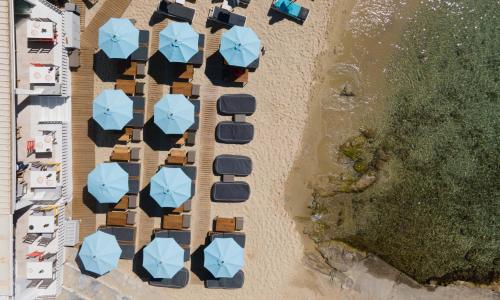 an overhead view of a beach with blue umbrellas at Argo Hotel in Platis Yialos Mykonos