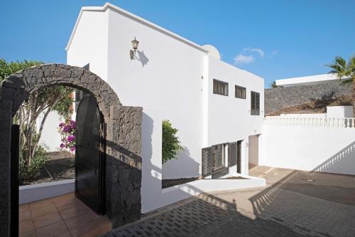 a white building with an archway and a door at Villa Carolina in Tías