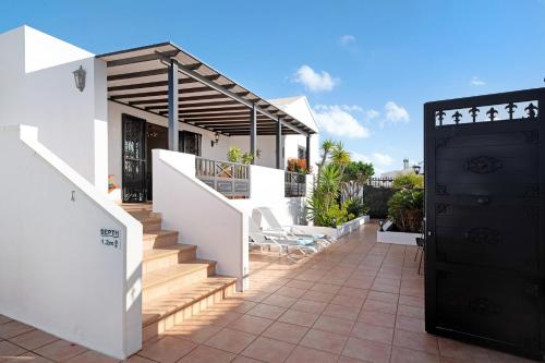 a house with a balcony with stairs and a black door at Villa Carolina in Tías