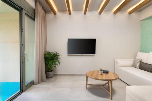 a living room with a couch and a tv on a wall at Villas Plumeria in Palaiochora