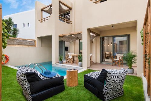 a house with a yard with grass and furniture at Villas Plumeria in Palaiochora
