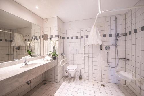 a bathroom with a shower and a toilet and a sink at Best Western Plaza Hotel Zwickau in Zwickau