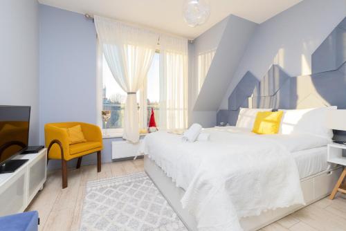 a blue and white bedroom with a bed and a yellow chair at Platinum Tartaczna Apartments by Renters in Gdańsk