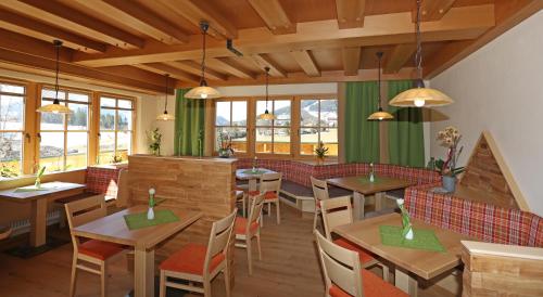 ein Restaurant mit Holztischen, Stühlen und Fenstern in der Unterkunft Alpenperle in Ramsau am Dachstein