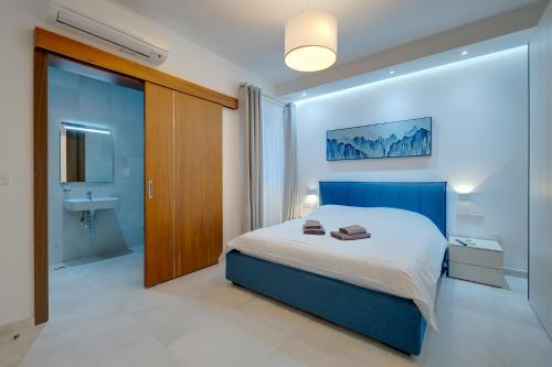 a bedroom with a blue bed and a bathroom at Superlative Apartment with Valletta and Harbour Views in Sliema
