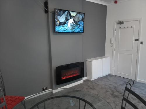 sala de estar con chimenea y TV en la pared en St Annes Lodge Apartments, Lytham St Annes, en Lytham St Annes