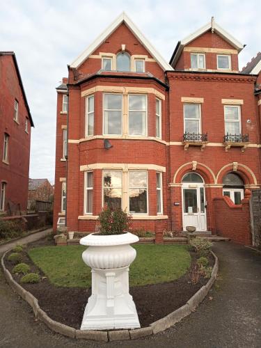 a large brick house with a white vase in front of it at St Annes Lodge Apartments, Lytham St Annes in Lytham St Annes