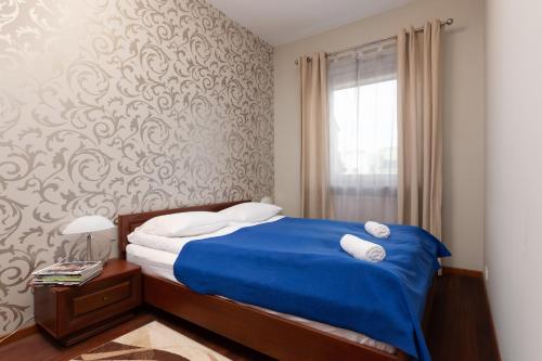 sypialnia z niebieskim łóżkiem i oknem w obiekcie Apartments Chełmońskiego Warsaw Ursus by Renters w Warszawie