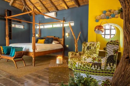 a bedroom with a bed and a couch and a chair at hippomoon lodge in Hoedspruit