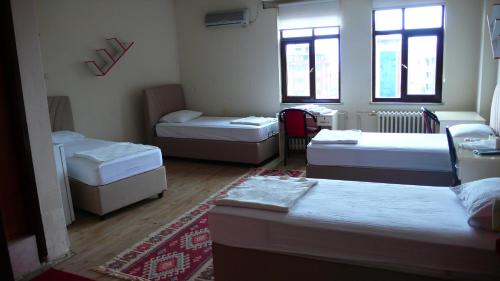 Habitación con 3 camas, sofá y ventanas. en Trabzon Star Pension, en Trabzon