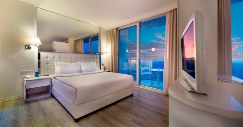 a bedroom with a white bed and a large window at Le Bleu Hotel & Resort Kusadasi in Kusadası