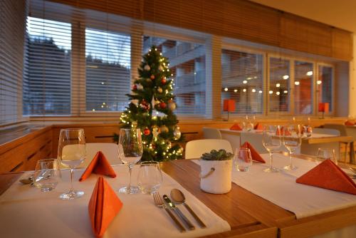 a table with a christmas tree in a restaurant at Omnia Hotel Relax & Wellness in Janske Lazne