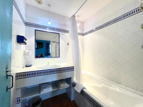 uma casa de banho com um lavatório, uma banheira e um espelho. em Irigoian em Bidart