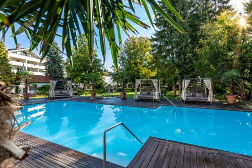 une grande piscine avec 2 chaises et des arbres dans l'établissement Das Parkhotel, à Bad Wörishofen