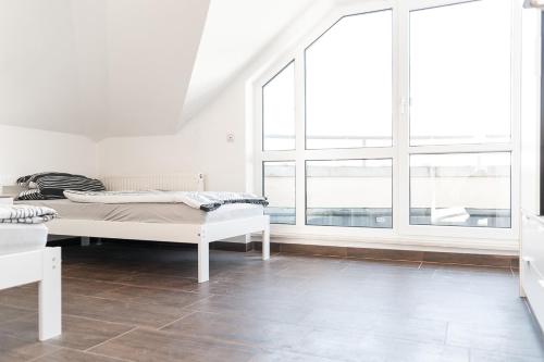 een witte kamer met een bed en grote ramen bij nJoy! Sunny & Simple - Dachterasse - gratis WLAN in Bad Friedrichshall