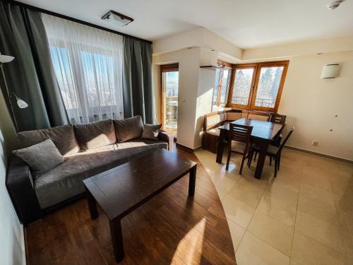 a living room with a couch and a table at Willa Pachówka - tam, gdzie natura spotyka się z nowoczesnością in Bukowina Tatrzańska