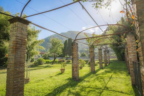 a row of arches in a garden with mountains in the background at Hotel Villa La Principessa in Lucca