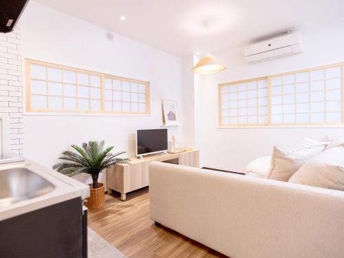 a white living room with a couch and a tv at Tsubame Hotel Asakusabashi 3 minutes walk from Asakusabashi Station Near Asakusa, Akihabara, and Ueno Cooking utensils and kitchen washing machine available Direct access to Haneda and Narita airports in Tokyo