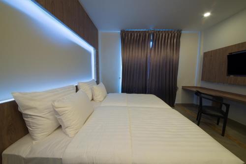 a bedroom with a bed with white sheets and a television at V20 Boutique Jacuzzi Hotel in Bangkok