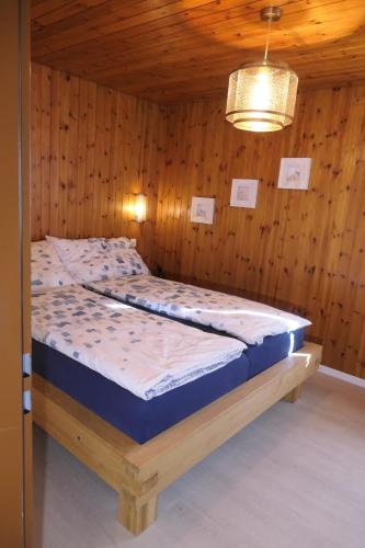 a bed in a room with a wooden wall at Chalet Valeria in Saas-Fee