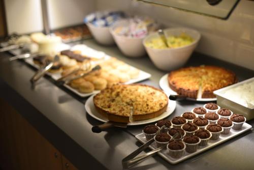 a counter with several different types of cakes and pastries at Holiday Inn Express - Paris - CDG Airport by IHG in Roissy-en-France