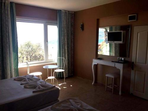 1 dormitorio con cama, escritorio y ventana en Sunset Hotel Dikili, en Dikili