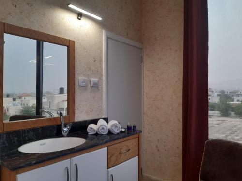 baño con lavabo, espejo y ventana en Dolphin Suites Hotel, en Jericó