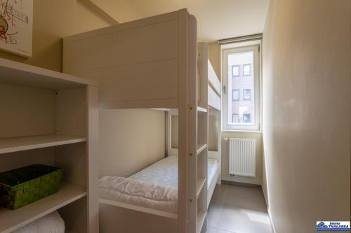 Ce lit superposé blanc se trouve dans un dortoir doté d'une fenêtre. dans l'établissement Alexy 0201, à Coxyde