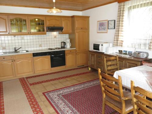 una cucina con armadi in legno, tavolo e sedie di Apartment Lassnig - ARR101 by Interhome ad Arriach