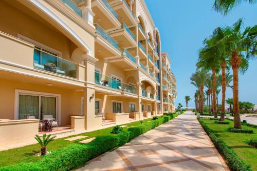 a large building with palm trees next to a sidewalk at Premier Le Reve Hotel & Spa Sahl Hasheesh - Adults Only 16 Years Plus in Hurghada