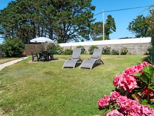 two chairs and an umbrella in a yard with pink flowers at Apartment Ty Ménez - GLN105 by Interhome in Goulien