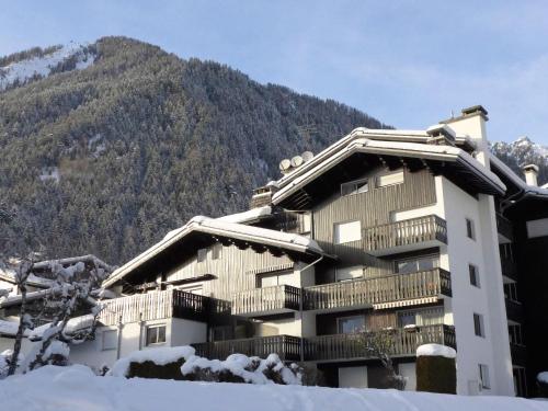 un bâtiment recouvert de neige avec une montagne en arrière-plan dans l'établissement Apartment Clos du Savoy-8 by Interhome, à Chamonix-Mont-Blanc
