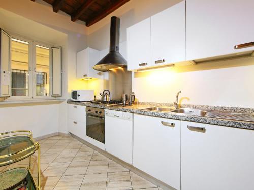 Apartment Vittorio Emanuele by Interhome في روما: مطبخ مع دواليب بيضاء ومغسلة