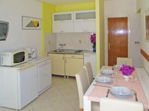 eine Küche und ein Esszimmer mit einem Tisch und einer Mikrowelle in der Unterkunft Apartment Palma - RAC108 by Interhome in Rabac