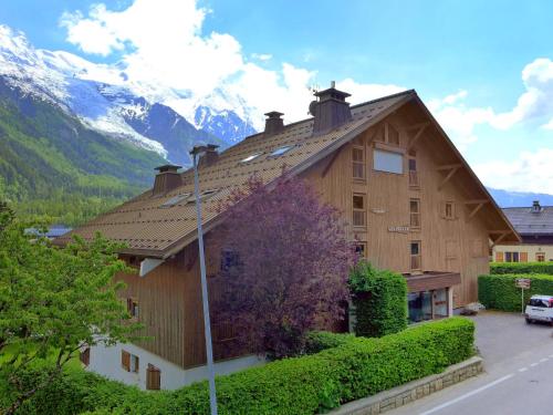 une grande maison en bois avec des montagnes en arrière-plan dans l'établissement Apartment Les Pècles by Interhome, à Chamonix-Mont-Blanc