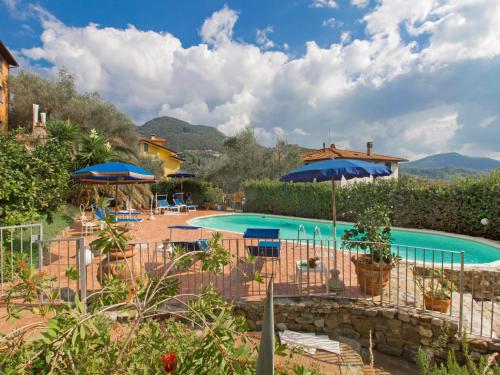 a pool at a resort with umbrellas and chairs at Apartment Alice by Interhome in Massarosa