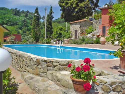 a swimming pool with a stone wall next to a house at Apartment Alice by Interhome in Massarosa