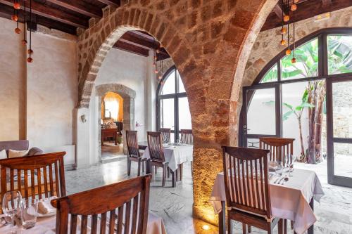 un comedor con mesas, sillas y ventanas en Spirit Of The Knights Boutique Hotel, en Rodas