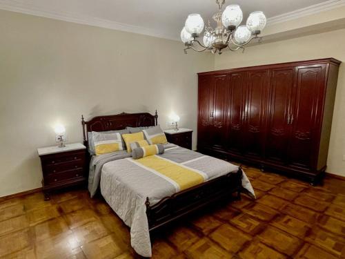 1 dormitorio con 1 cama, suelo de madera y lámpara de araña. en PRECIOSO PISO CENTRO, en Ourense