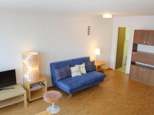 sala de estar con sofá azul y TV en Apartment Beaulieu-2 by Interhome, en Zermatt