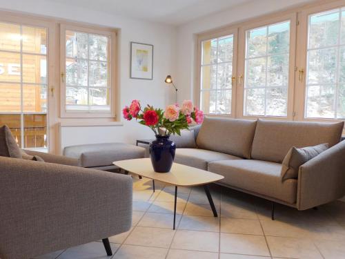 a living room with a couch and a table with flowers at Apartment Obri Tuftra-4 by Interhome in Zermatt