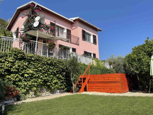 una casa rosa con una valla de madera delante de ella en Apartment Villa Paradiso - DOL190 by Interhome, en Dolcedo